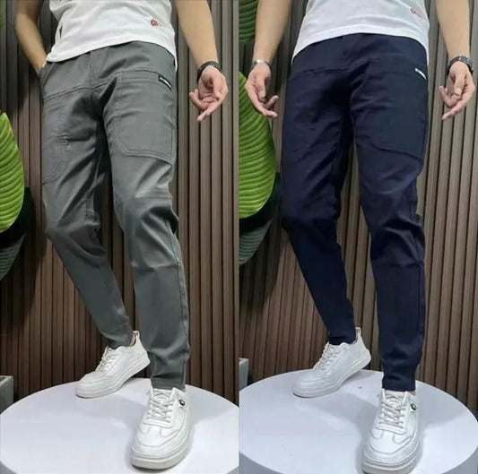 Casual men's jogger pants in gray and navy colors, displayed on a platform with white sneakers.