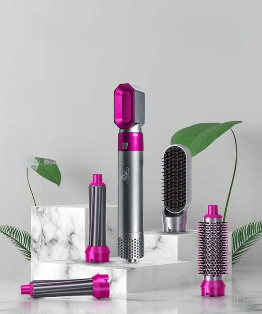 5-in-1 multifunctional hair styling tool, featuring a detachable hot air comb, automatic suction hair curler, and sleek pink and grey design, displayed on a marble-like surface with tropical leaves.