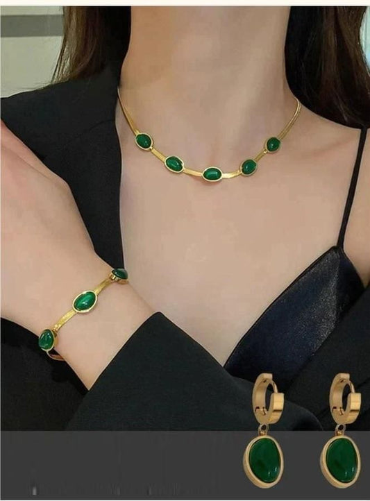 Elegant green crystal pendant necklace set with matching bracelet, showcased on a woman wearing a black dress against a neutral background.