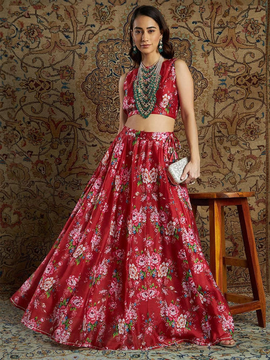 Elegant Floral Chanderi Crop Top and Skirt Set - A vibrant red and gold floral patterned women's Indian outfit featuring a sleeveless crop top and floor-length floral printed skirt, presented against an ornate textured background.